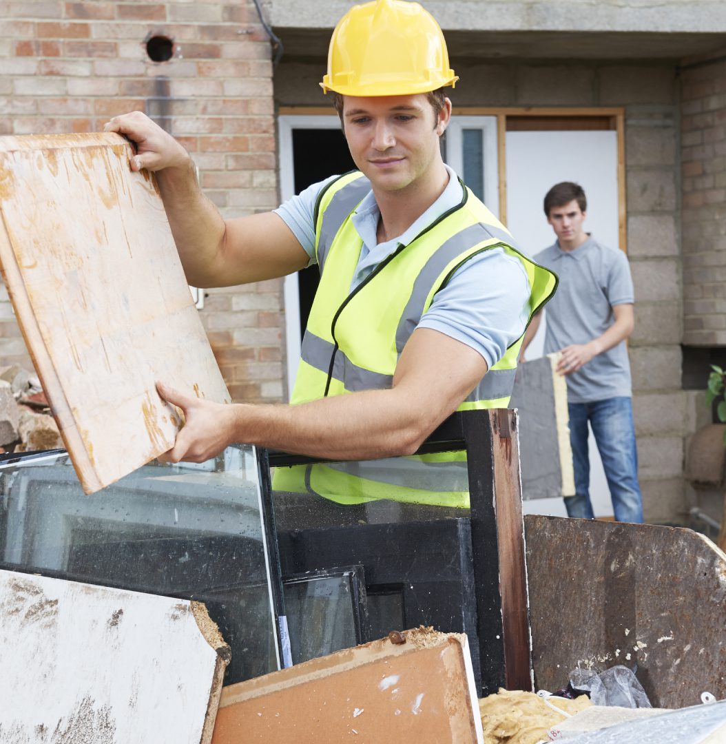 Construction workers sorting materials in skip.