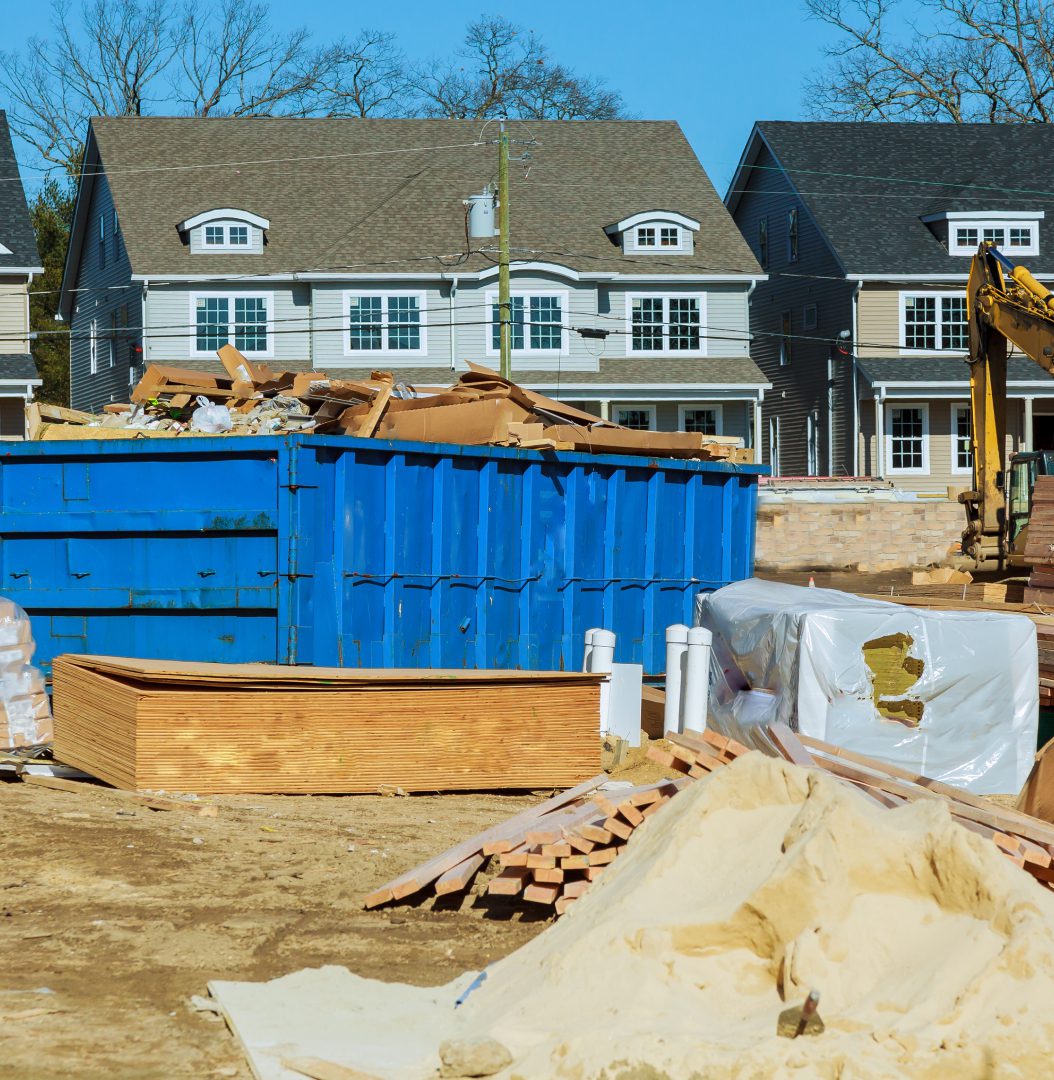 Construction site with materials and blue dumpster.