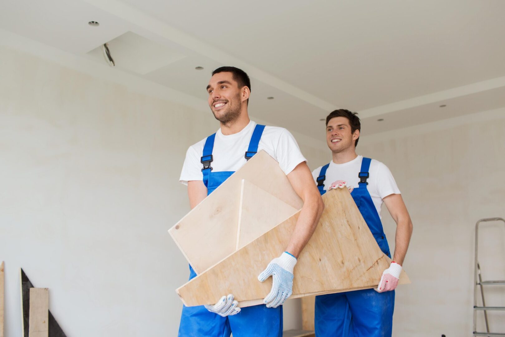 Workers carrying wooden boards in a room.