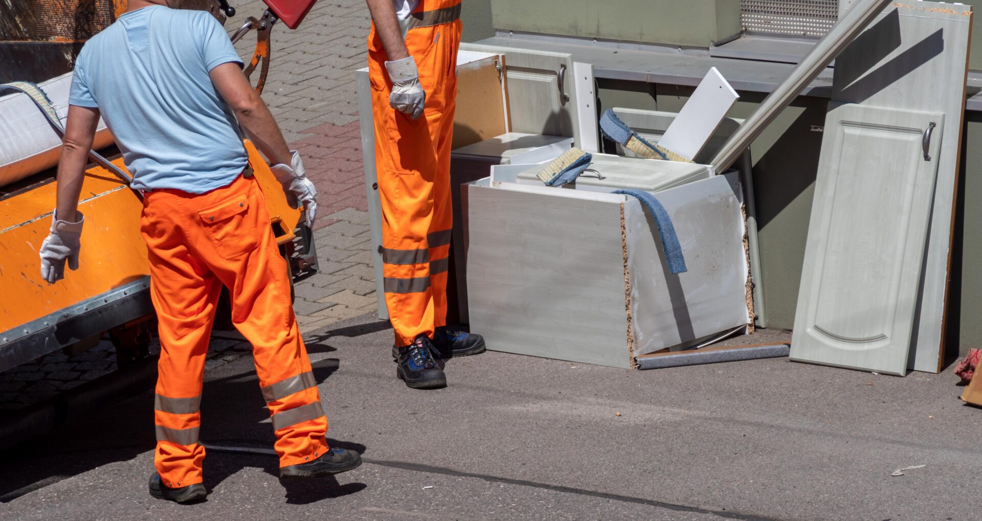 Workers handling discarded household items on street.