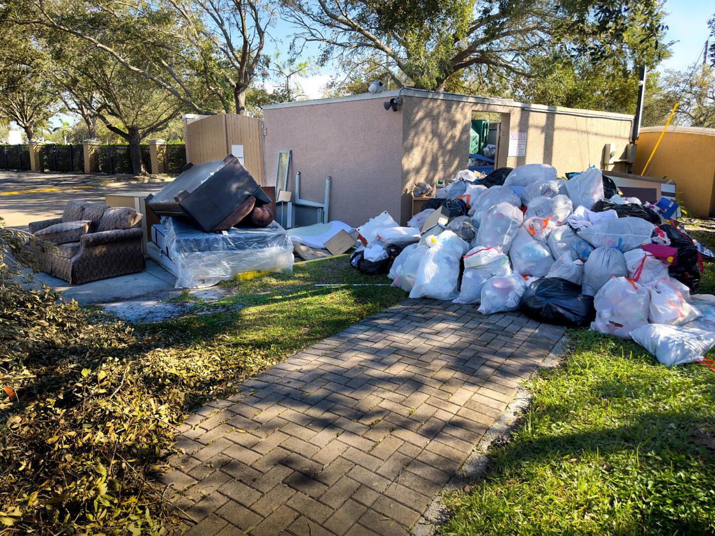 Garbage bags and furniture beside a building.
